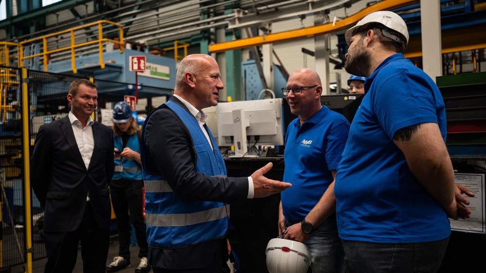 Berlins Bürgermeister Kai Wegner im Gespräch mit zugewanderten Arbeitskräften in einem Aluminiumwerk.