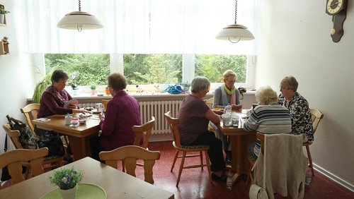 Eine Gruppe von Senioren sitzt beisammen und spielt Karten.