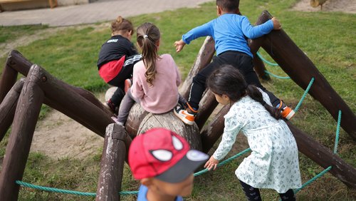 Mehrere Kleinkinder turnen auf einem Spielgerät auf dem Spielplatz