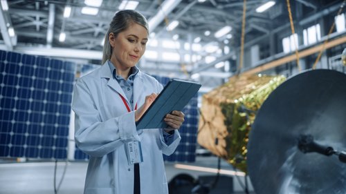 Weibliche Ingenieurin verwendet Tablet-Computer während der Arbeit an Satelliten-Konstruktion. 